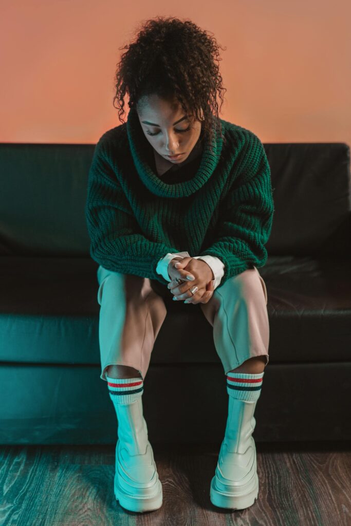 Portrait of a stylish young Black woman deep in thought, wearing a cozy turtleneck sweater indoors.