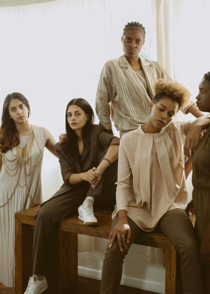 A diverse group of women posing in stylish outfits, showcasing modern fashion indoors.