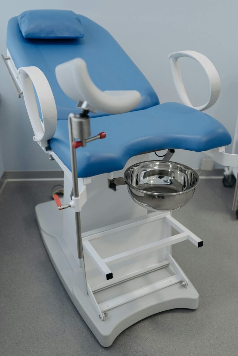 Medical facility showcasing a modern gynecological examination chair with blue upholstery and sterile environment.